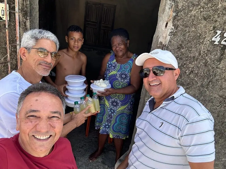 Voluntários entregando marmitas e sorrindo junto às pessoas atendidas