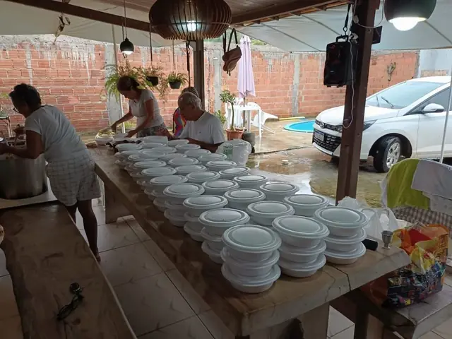 Mesa com dezenas de marmitas sendo montadas